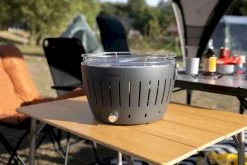 LotusGrill XL Hybrid Houtskoolbarbecue - Rood -Winkel Voor Kampeerartikelen lotusgrill in zon op tafel 3